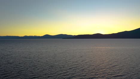 drone flying through pine trees towards beautiful mountain lake sunset over lake tahoe in the sierra nevada mountains california usa - aerial