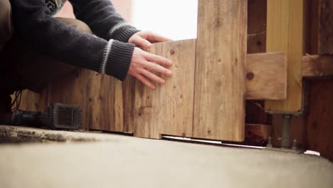 installing cut wood pallet on wall with electric drill as screwdriver