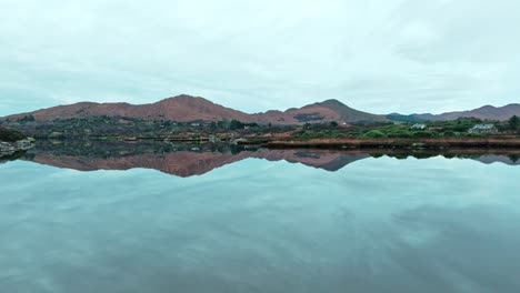 Drone-flying-to-the-mountains-over-still-waters-and-inlets-Ring-Of-Kerry-Ireland-on-the-wild-Atlantic-way-in-autumn