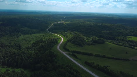 aerial view of a winding road through a lush forest landscape