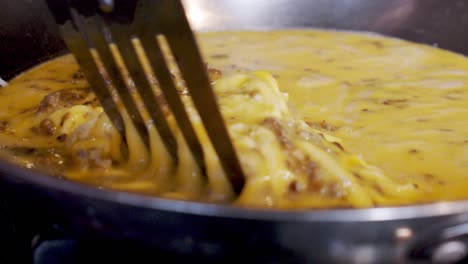 wide shot cooking sausage eggs in pan on stovetop in slow motion