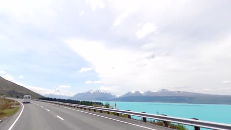 Driving-allow-the-shore-of-lake-Pukaki-with-a-beautiful-view-of-the-glacial-water-and-snow-peaked-mountain-range