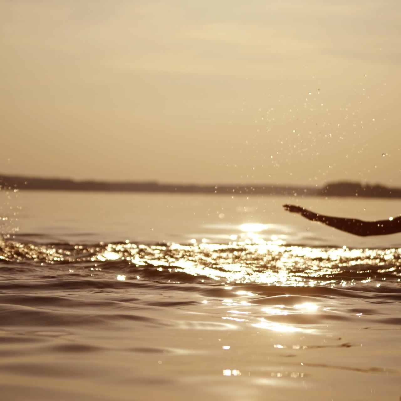 Happy boys are jumping and making splashes in water at sunset. Silhouette of two cheerful brothers having fun in water in the evening. Summer fun.