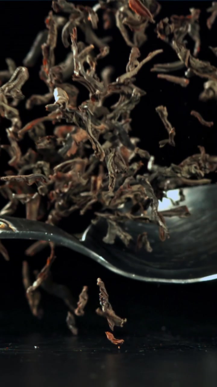 Dry Tea Leaves Falling from a Spoon in Slow Motion
