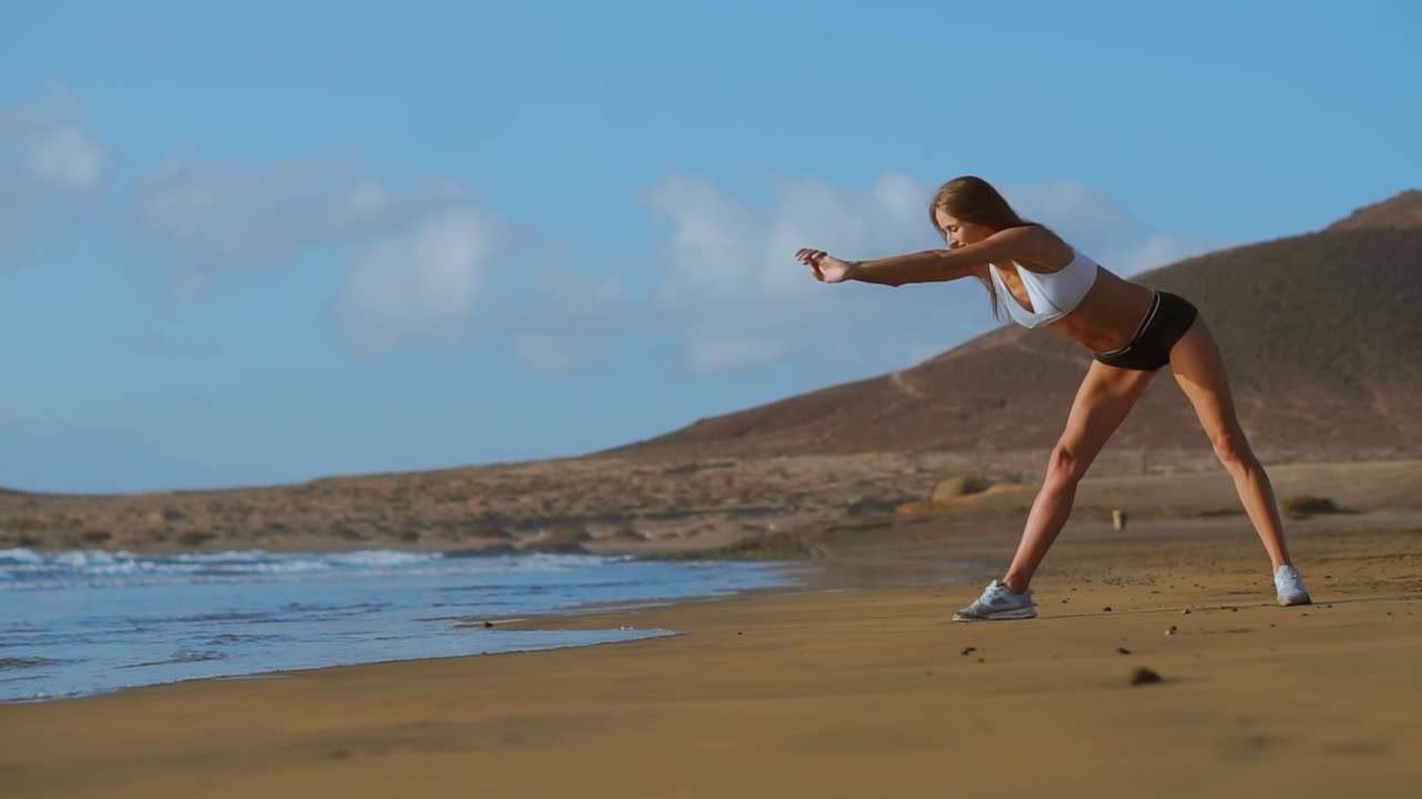 mujer estirando las piernas y los isquiotibiales haciendo postura de yoga de estiramiento en la playa. mujer de fitness relajándose y practicando deporte y yoga.