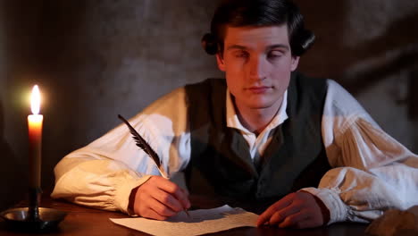 young man writing with a quill pen by candlelight
