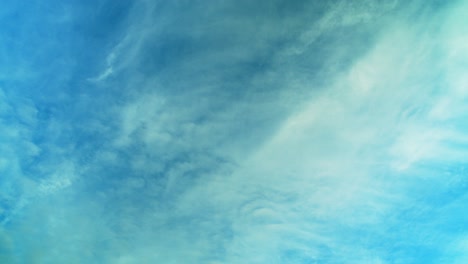 Clouds-move-in-two-directions-through-azure-blue-sky,-background