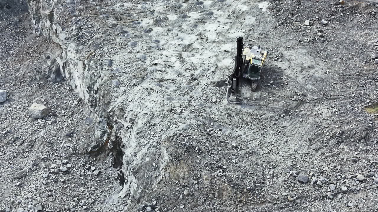 Attività in una cava di granito con macchinari pesanti che estraggono pietra dal terreno in una grande cava a cielo aperto, durante le ore diurne.