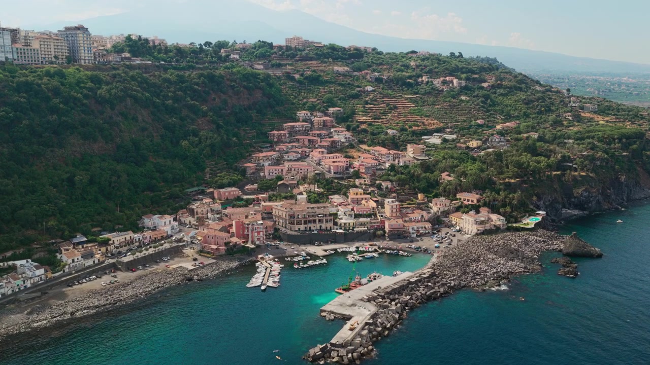 Ripresa aerea all'ora d'oro di Santa Maria la Scala, un villaggio di pescatori circondato da scogliere di lava basaltica nera vicino all'Etna ad Acireale, Catania, Sicilia, Italia, una destinazione popolare sulla costa ionica