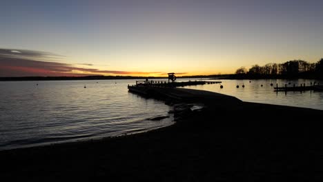 Strand,-Sonnenuntergang-Am-See-Mit-Einem-Mann,-Der-Auf-Einem-Ponton-Läuft