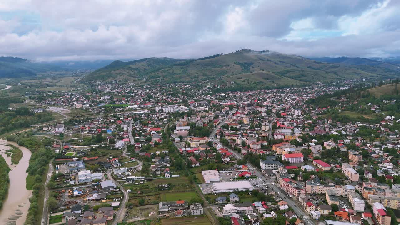 Drone footage of Gura Humorului city on a cloudy day, showing buildings and the Moldova River