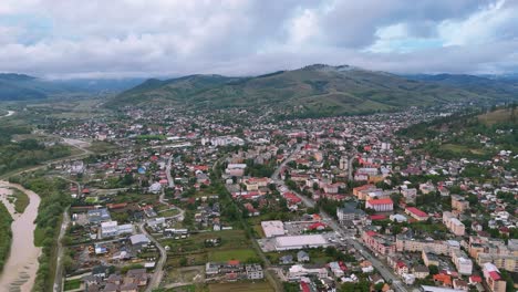 drone footage of gura humorului city on a cloudy day, showing buildings and the moldova river