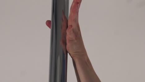 primer plano de una mano femenina agarrando un poste de poledance