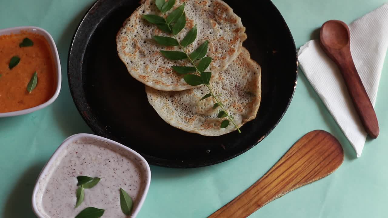 oothappam giratorio - dosa - desayuno del sur de la india con arroz, lentejas y verduras servidas con chutney de coco aislado sobre fondo verde