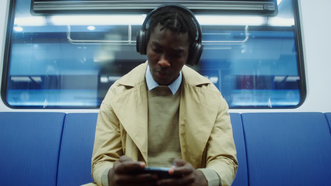 Man with headphones using smartphone on a subway train