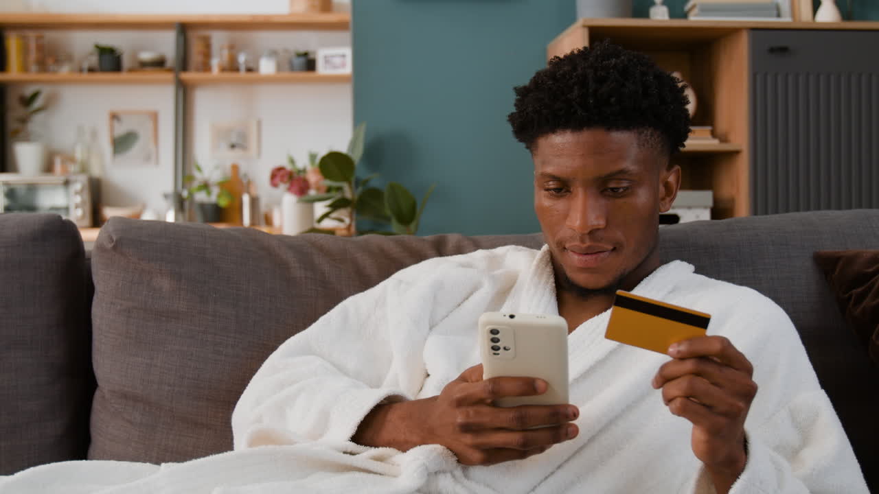 Man using smartphone and credit card for online shopping at home
