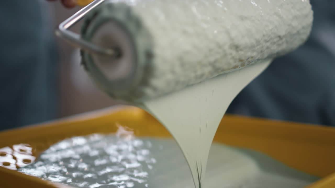 bandeja amarilla de primer plano y rodillo de pintura con color blanco en él. concepto diy.