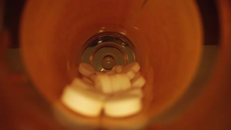 pulling-out-of-the-entire-length-of-a-orange-prescription-pill-bottle,-revealing-empty-blue-bottle-cap