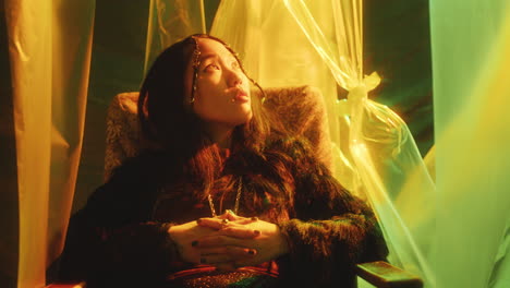 portrait of pretty asian model sitting in armchair in studio with neon light