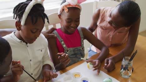 african american family painting easter eggs together at home