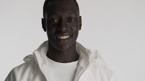 un hombre afroamericano sonriente sobre un fondo gris.