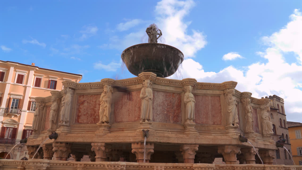 Central fountain surrounded by historic buildings and arches in main square of Perugia