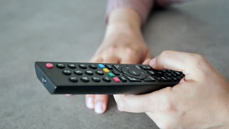 close up of women hand holding tv remote