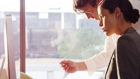 Businesswoman-working-with-colleague-at-desk