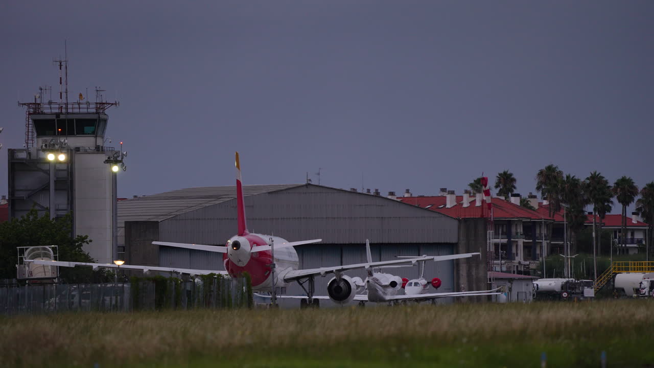 Mobile boarding stairs retracting from stationary airplane on airport apron during cloudy evening