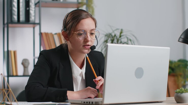 Podnikatelka pracuje na notebooku a má na sobě sluchátka operátora podpory call centra v kanceláři