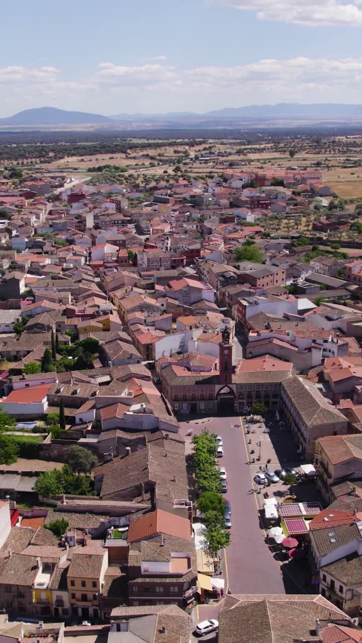 Órbita aérea vertical capturando el barrio tradicional de Oropesa y el luminoso campo circundante.