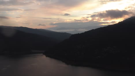 Vista-Aérea-De-La-Puesta-De-Sol-Sobre-Una-Colina-Con-Un-Impresionante-Lago-En-Primer-Plano