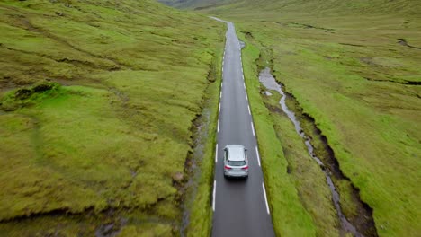 a car driving on a scenic road through lush green fields in the faroe islands