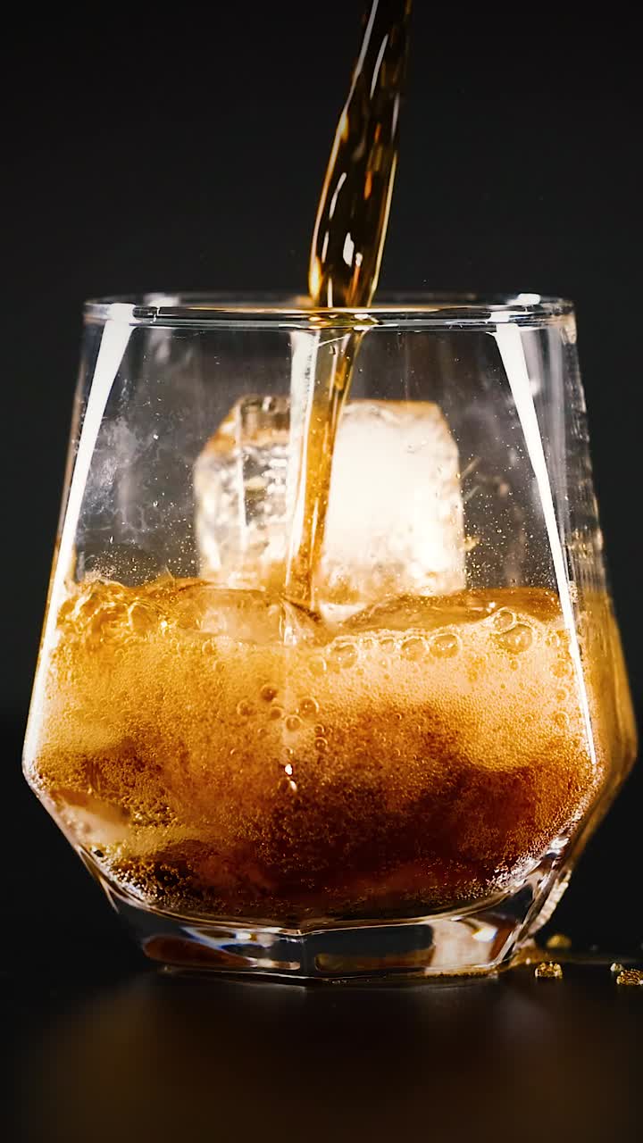cola siendo vertida sobre el hielo en un vaso