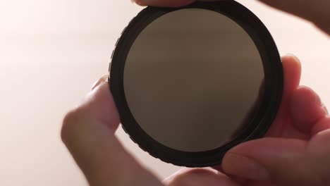 photographic camera equipment filter isolated on white background. concept. female hands demonstrating the effect of polarizing filter for camera lens.