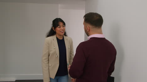 male and female teachers meeting and talking as they walk along corridor in school building