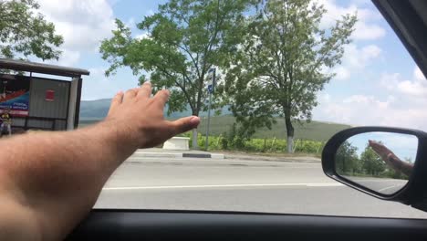 driver man hand playing with wind at window car on a highway.