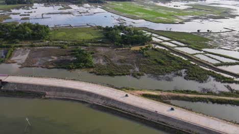 Aerial-video-of-a-road-in-the-middle-of-the-flooded-farmlands-in-Bholaganj,-Bangladesh