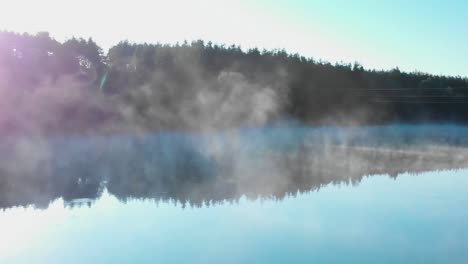 Sunrise-over-forest-in-front-of-foggy-lake---panning-shot,-59