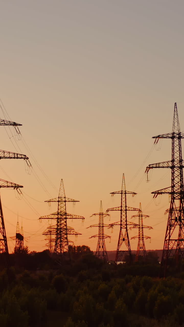 High voltage electric towers at sunset. Transmission power line. Parts of electrical equipment and high voltage power line insulators in the evening. Vertical video