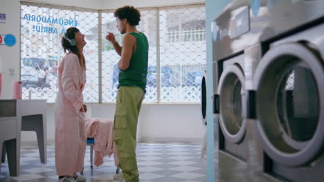 joyful couple dancing together in laundry service. multicultural teenagers have