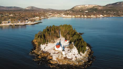 aerial flyby and tilt down over snow covered curtis island lighthouse at sunrise with long shadows in the snow