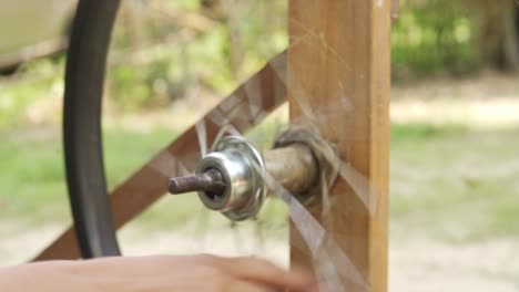 usando una rueda de bicicleta para tejer algodón de seda en un taller en una aldea rural de la india