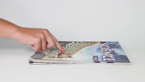 hands flipping pages of a science-themed magazine