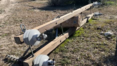 electrical distribution double wooden cross-arm with Hendrix vice top insulators attached laying on on the ground under construction