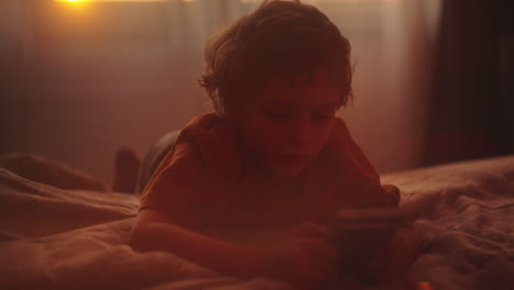 child using phone in bed at sunset