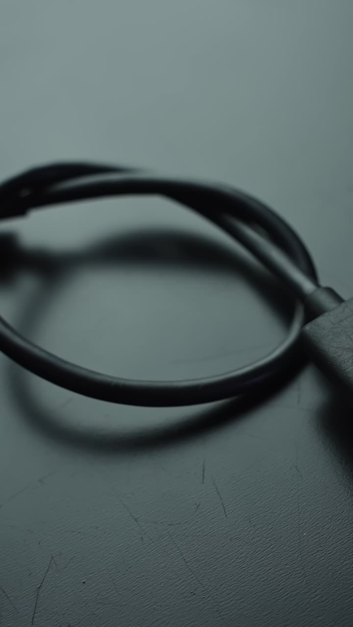 Vertical macro of a USB-A plug and USB-C cable on a gray desk as the camera pans left, soft bokeh and copy space, calm minimal tech vibe