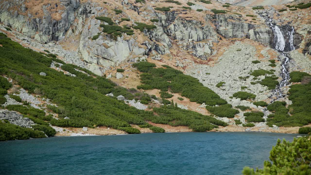 el agua del lago de color azul turquesa oscuro se reúne en la base de la cascada en sliezsky dom, alta tatra eslovaquia