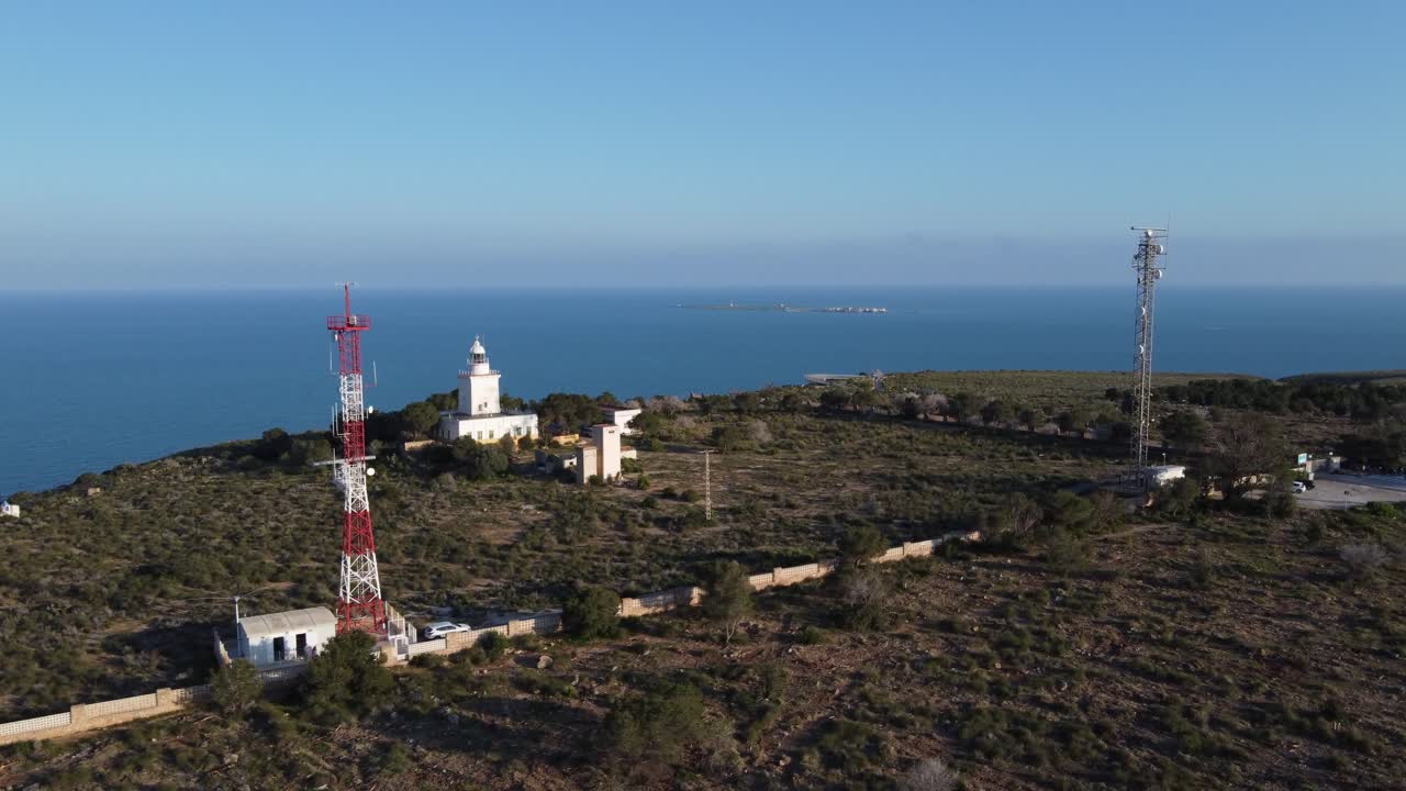 Hidas ilmasta laskeutuminen näyttäen majakan sekä viestintä- ja tunnistusantennit, meri ja Tabarcan saari taustalla. Santa Pola, Espanja.