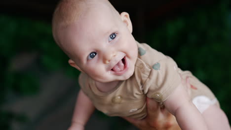 adorable caucasian infant boy smiling adorably. parent's hand holding a child. close up. blurred backdrop.